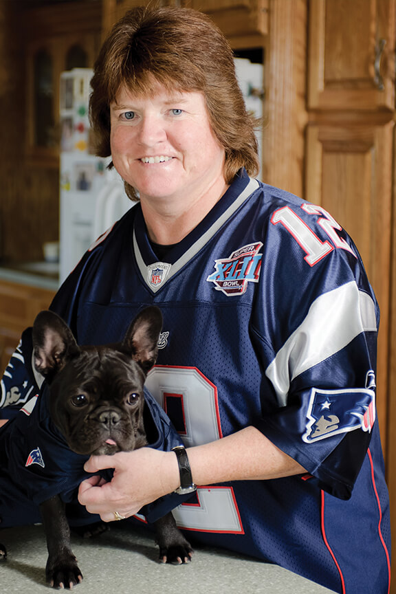 Kara pictured with a Frenchie in her home - both wearing football jerseys