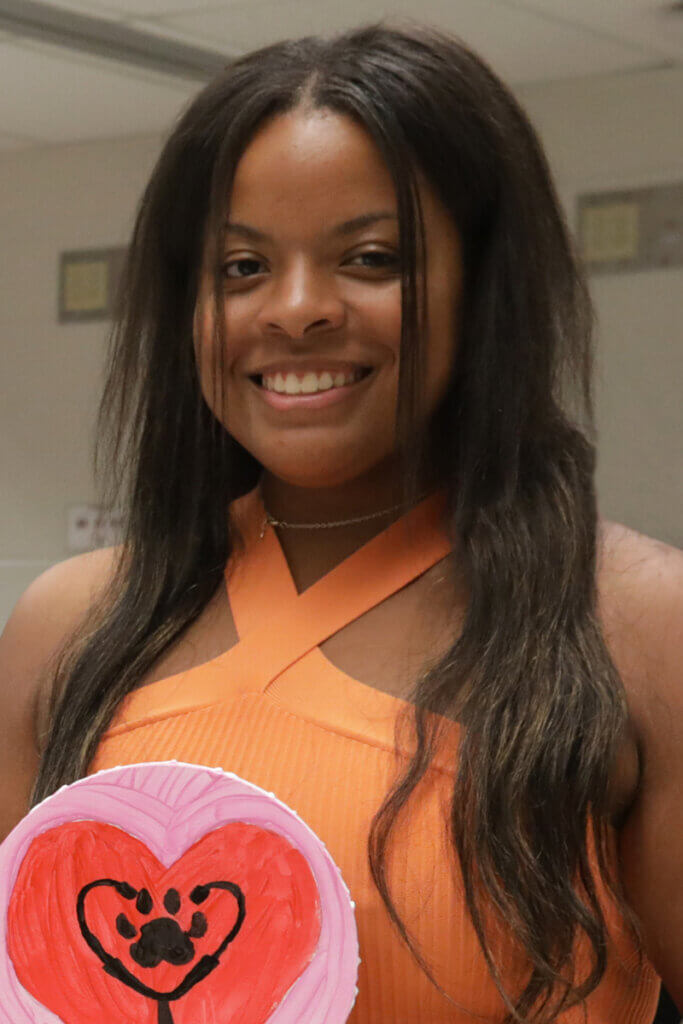 Kennedi holds up a small painting canvas with a paw print and stethoscope inside a heart during student orientation earlier this year