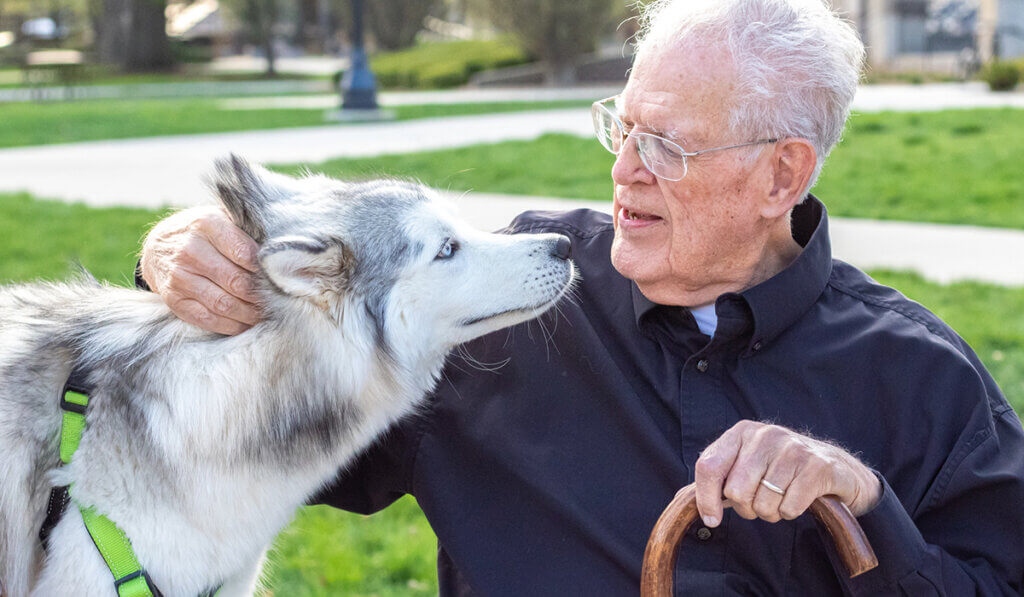 Dr. Pickett sits close with a Husky dog