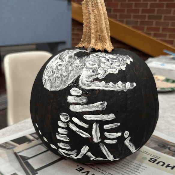 pumpkin painted black with a white skeleton painted on top