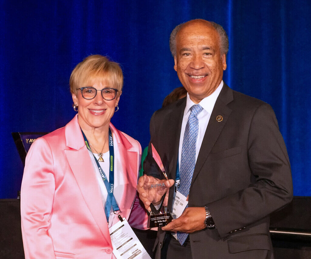 Dean Reed stands next to the AVMA President as he holds up his award plaque