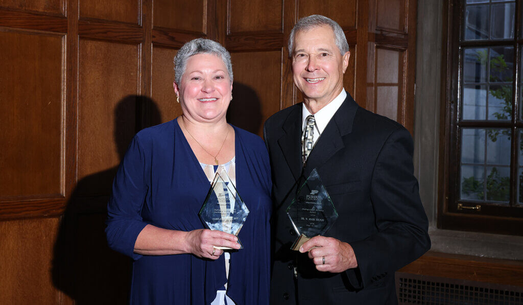 Pam Phegley and Mark Hilton stand together holding up their award plaques