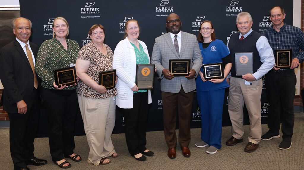 Dean Reed stands next to the award-winning faculty as they hold up their award plaques