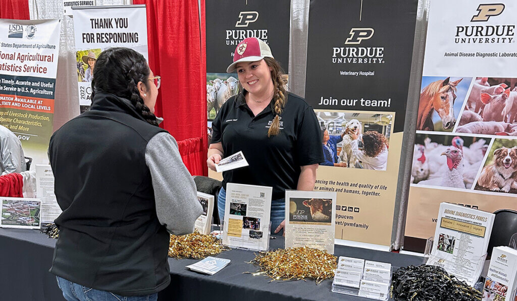 Adrianna hands a flyer to a beef producer who stopped by the college's booth in the exhibit hall.
