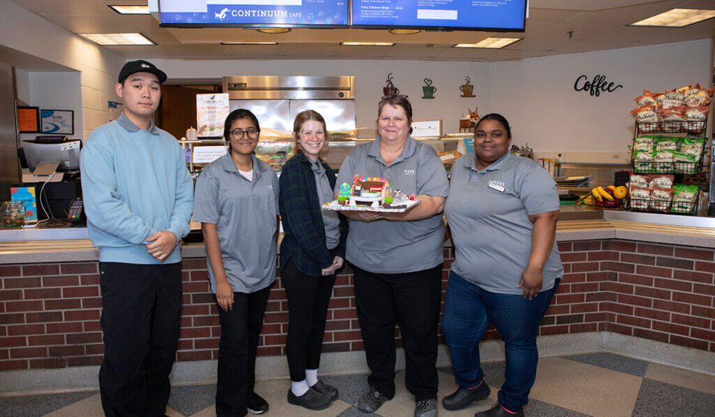 The café team poses together with their gingerbread house creation in the Continuum Café.