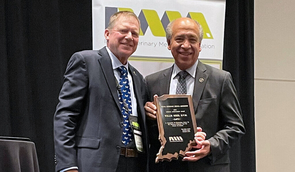 Greg Kurtz and Dean Reed stand together on stage as the dean holds up his award plaque