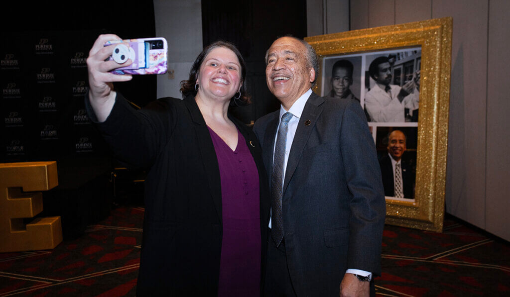 Dr. Hedges and Dean Reed smile as she snaps a photo of them with her phone