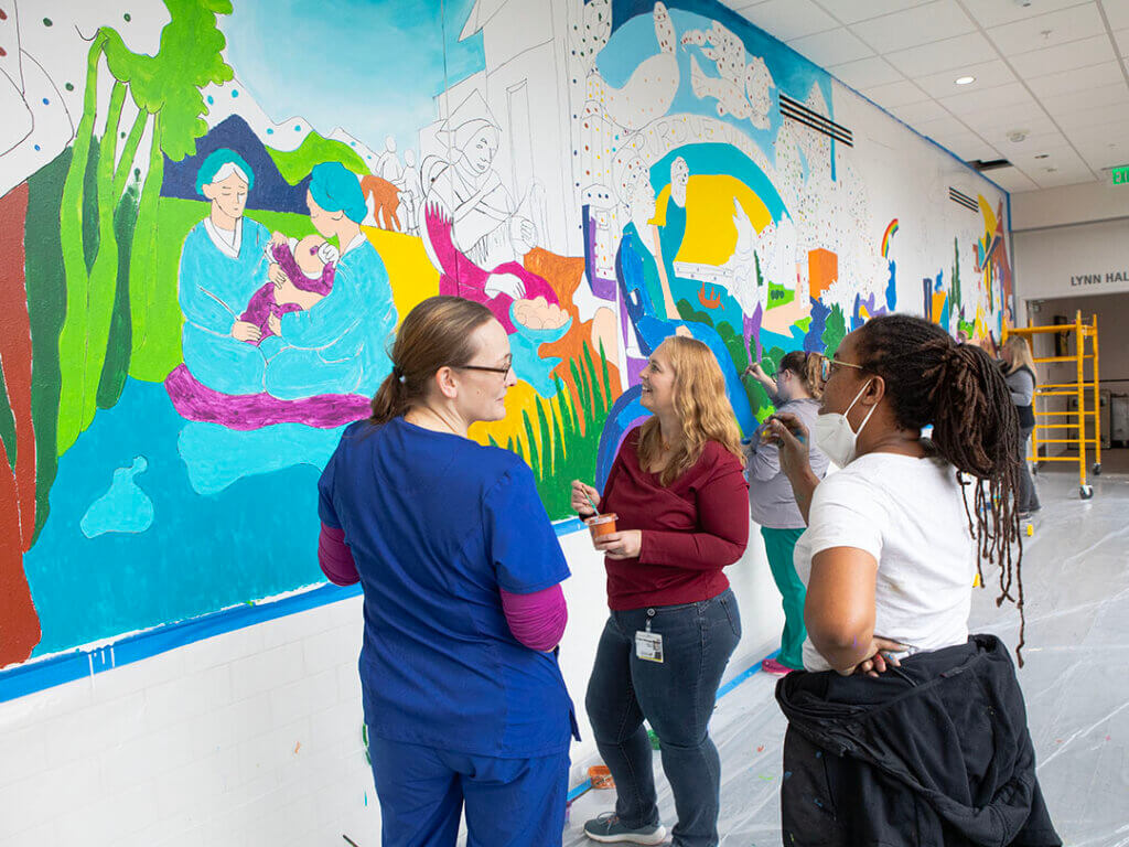 Tia Richardson, Dr. Brooks, and Dr. Corriveau talk while standing in front of the mural in progress