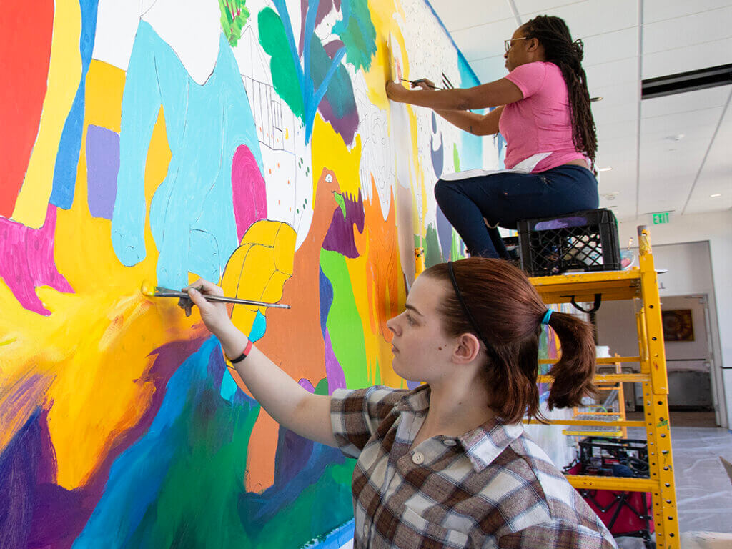 students help paint the mural