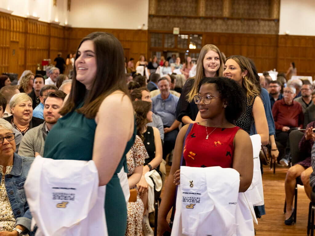 Members of the Class of 2025 hold their white coats as they process through the Purdue Memorial Union South Ballroom to their seats at the start of the White Coat Ceremony.