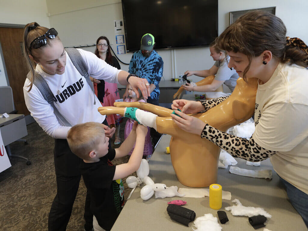 Dr. Brittany Bertsch (PU DVM 2016) guides her son as he tries his hand at bandaging in the Veterinary Nursing display area.  
