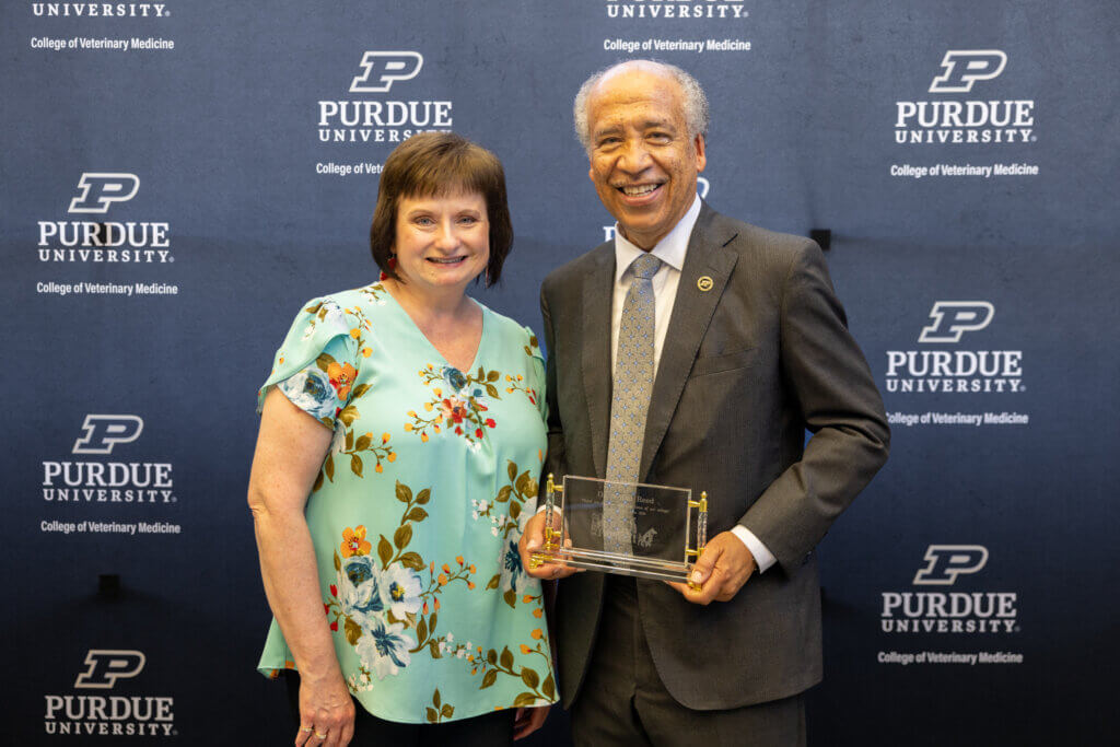 Dean Reed displays the recognition gift he received from the college as he is joined by reception co-host and PVM Principal Operations Administrator Lee Ann for a photo op.