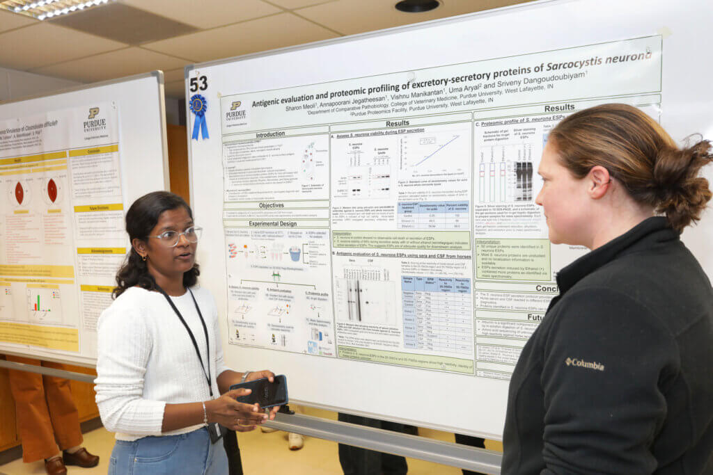 Sharon Meoli, of the DVM Class of 2025, talks to a Research Poster Session attendee about her First Place poster in the DVM Student Research category, entitled, “Antigenic Evaluation and Proteomic Profiling of Excretory-Secretory Proteins of Sarcocystis Neuron.”