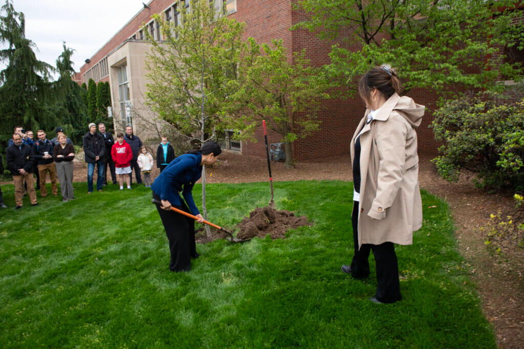 Guided by Purdue Landscape Architect Brooke Sammons (foreground) Joyce helped shovel dirt around the base of the tree and was followed by other attendees who wanted to participate in the same way.