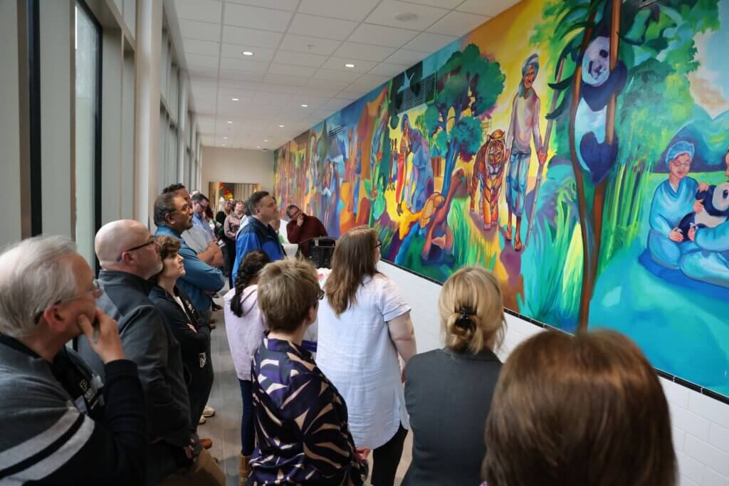 Dedication ceremony guests admired the mural as Tia described the scenes depicted in it.