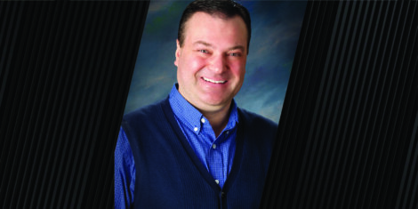 portrait of man wearing a blue button up shirt with a dark blue vest