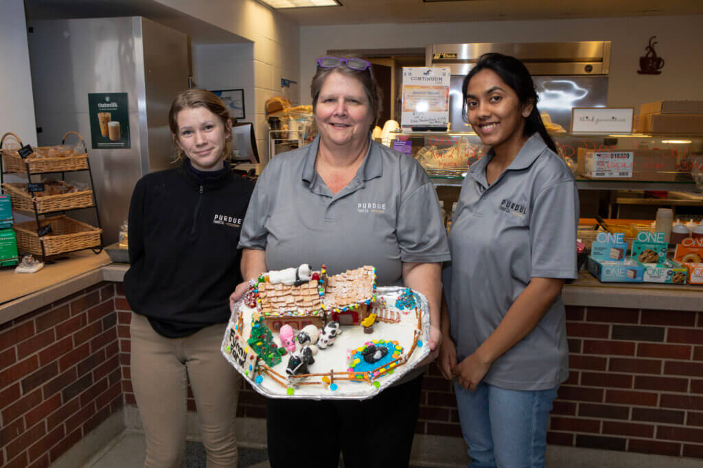 The Continuum Café team of Tammie Hill (center), Rebecca Watkins (left) and Samhita Irriki captured 2nd place with “Funny Farm,” which was their entry in the Purdue Food Company’s 2024 Gingerbread House competition.