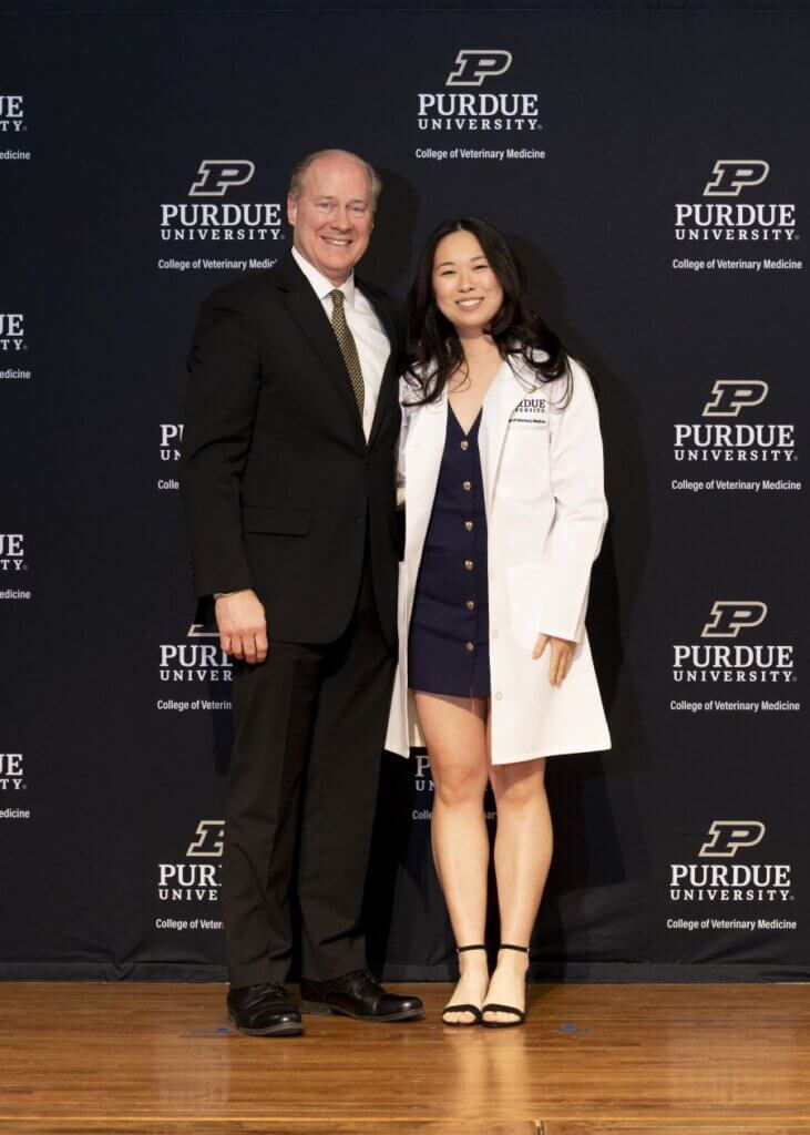 Dean Marsh pauses for a photo after placing a white coat on veterinary student Yonghua “Jenn” Hu.