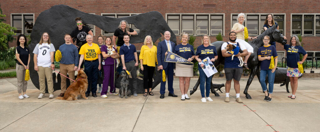 Staff and Faculty members of Purdue University College of Veterinary Medicine standing at the Continuum outside Lynn Hall