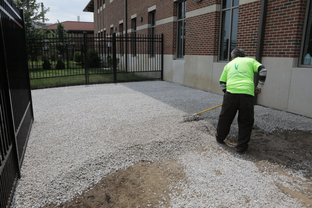 A worker for Forever Lawn of Northeast Indiana prepares the ground in the dog run for the new layer of synthetic turf.