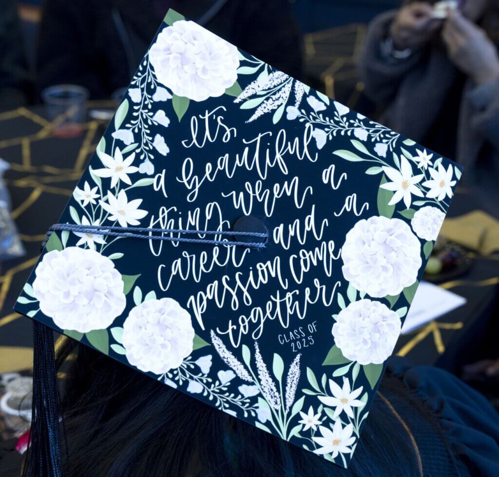 The top of a graduation cap that is decorated in a floral pattern and reads "It's a beautiful thing when a career and a passion come together. Class of 2025"