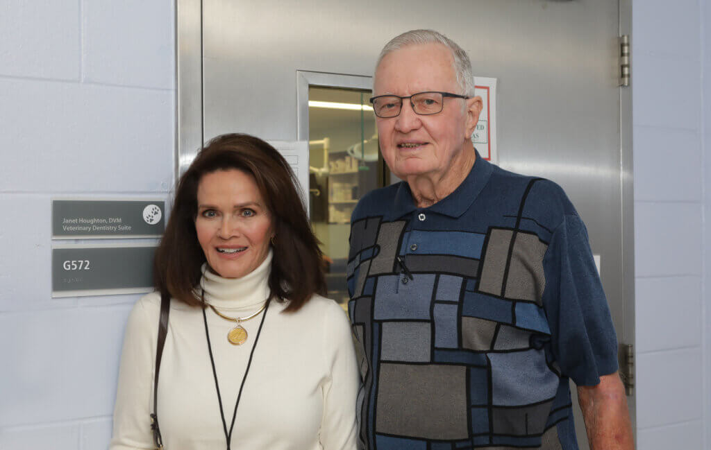 a man and woman are facing the camera posed in front of a metal door