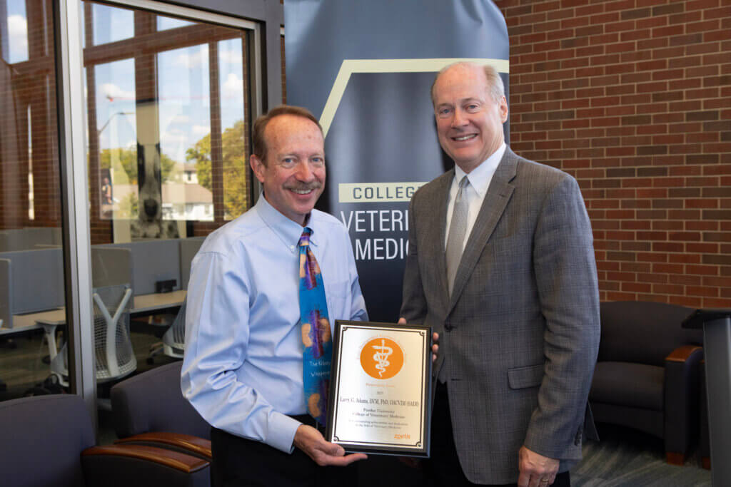 two men standing and posed for a picture, while one man holds a plaque