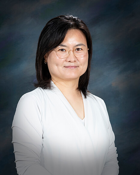 portrait of a woman wearing glasses and a white shirt, posed in front of a dark blue background