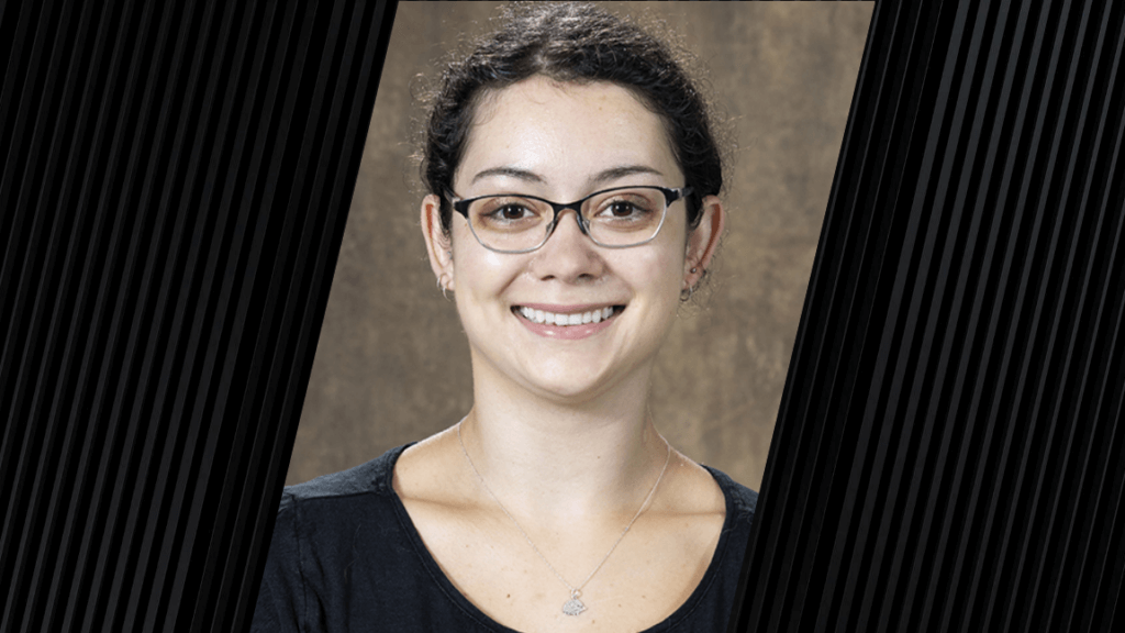 Portrait of a woman with dark hair, wearing glasses and a black shirt