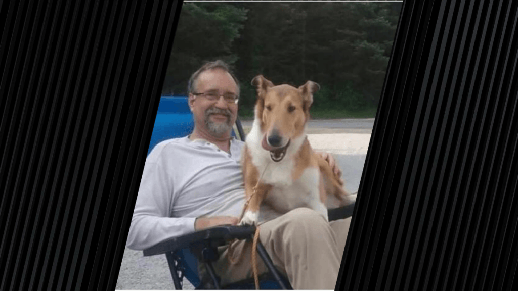A man is sitting in a chair and has a dog on his lap. The man is wearing a long sleeve white shirt