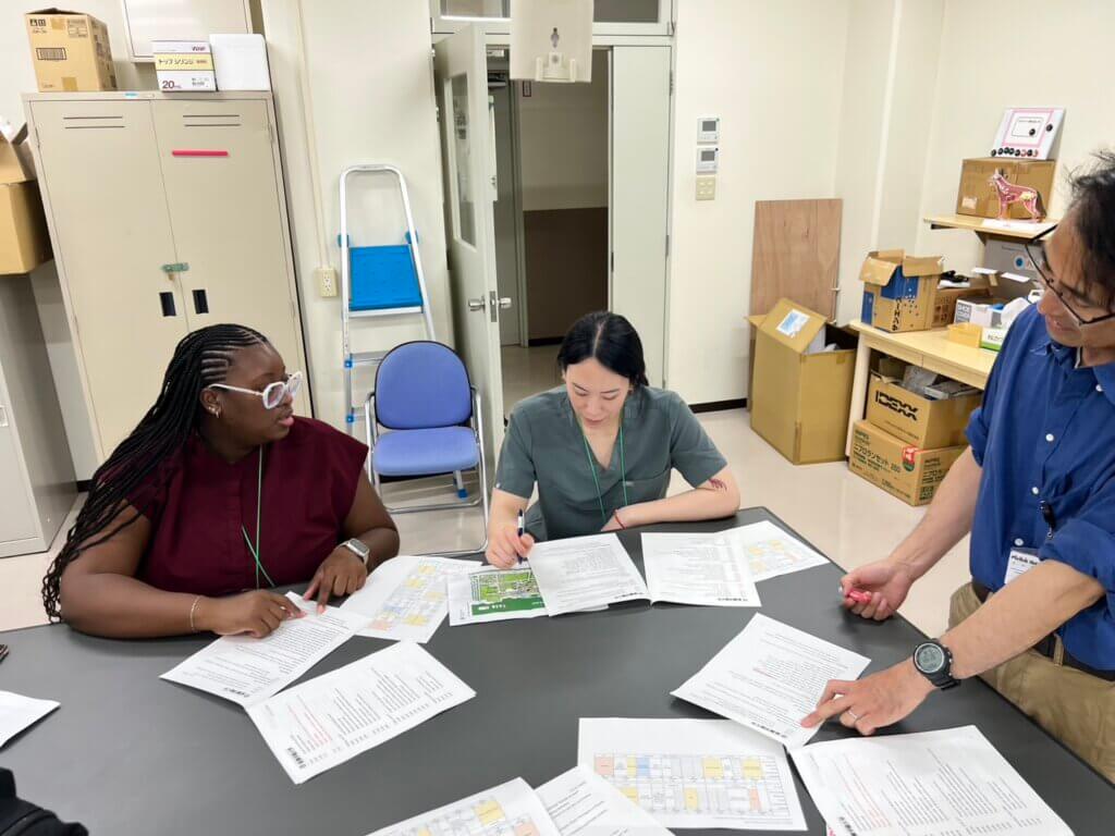 Two females are sitting at a table with several papers scattered. They appear to be doing paperwork or studying for an exam.