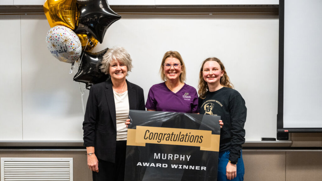 three women are standing in front of a white board and are holding a banner that says "Contratulations Murphy Award Winner"