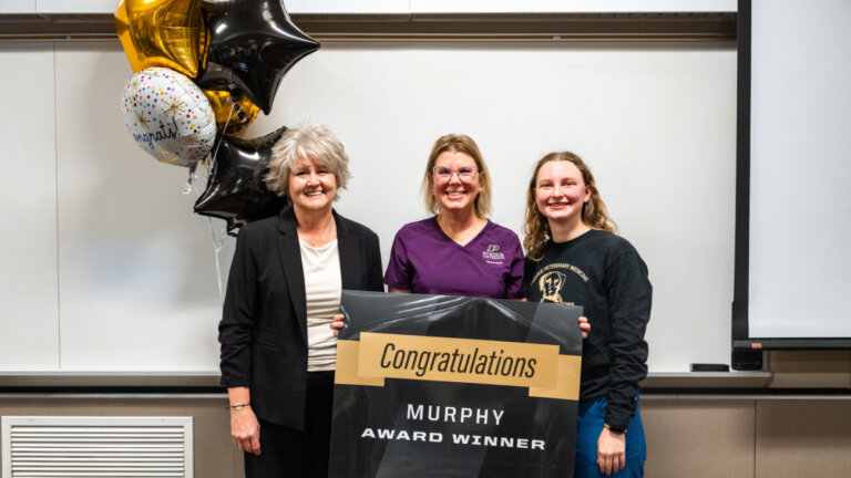 three women are standing in front of a white board and are holding a banner that says "Contratulations Murphy Award Winner"