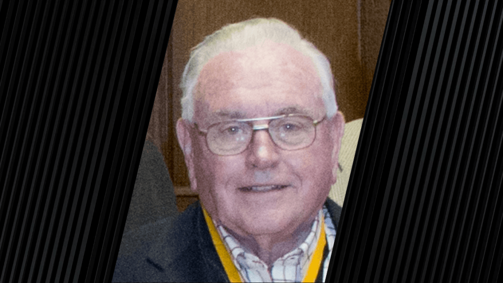 man with white hair is wearing glasses and a black and gold lanyard