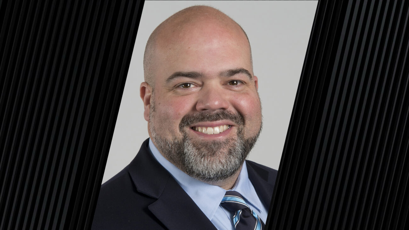 portrait of a man wearing a light blue dress shirt, a dark jacket and a tie