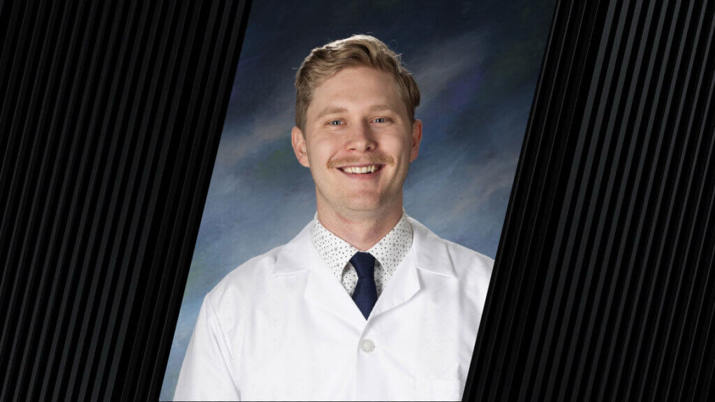 A man wearing a white coat, dark blue tie and a white polka dot dress shirt