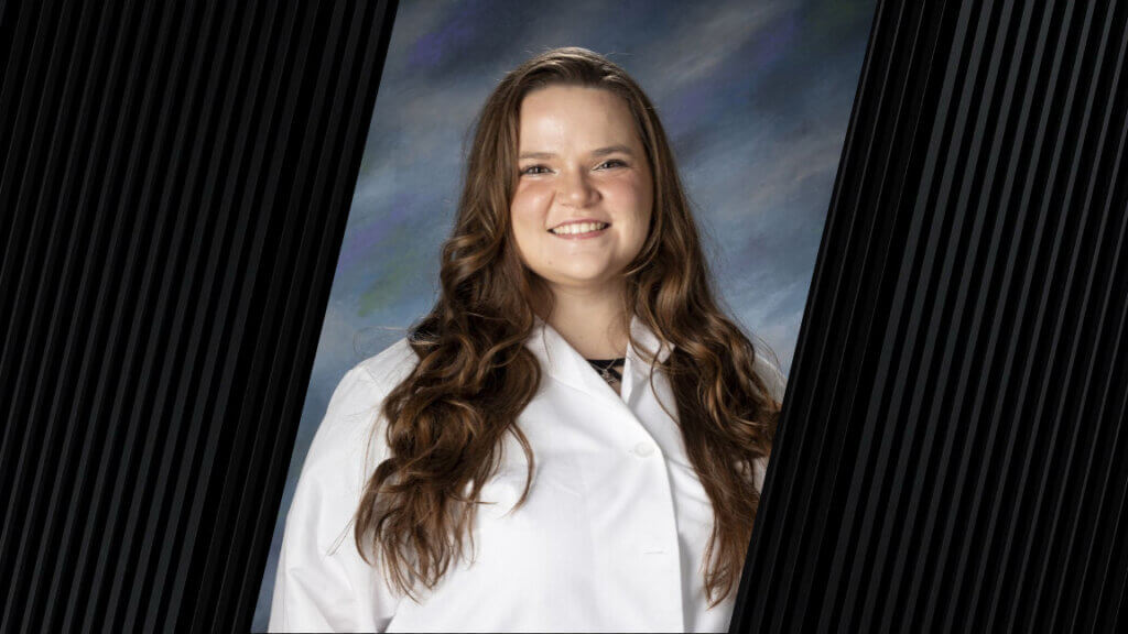 A female with long brown hair is wearing a white medical coat