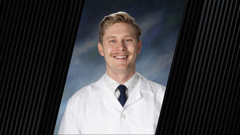 A man wearing a white coat, dark blue tie and a white polka dot dress shirt