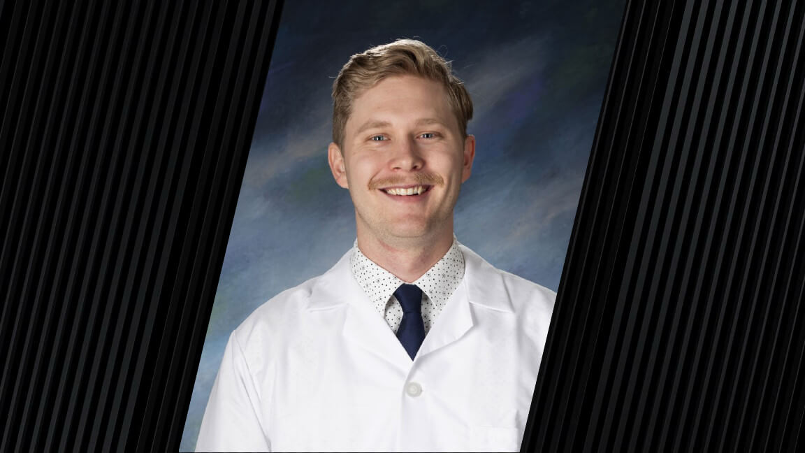A man wearing a white coat, dark blue tie and a white polka dot dress shirt