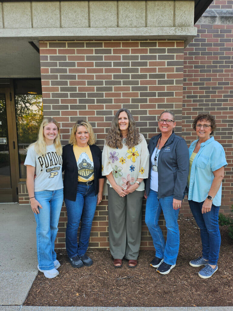 A group of women standing outdoors in front of a brick wall