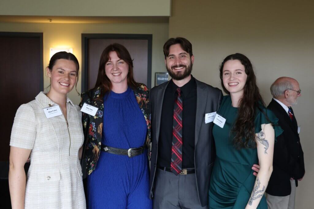 Four young adults are grouped together and wearing business formal attire