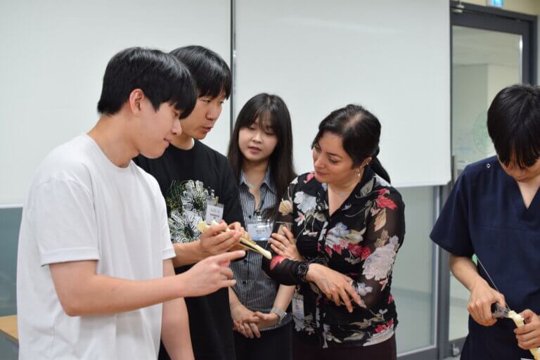 A bone is being examined by a group of adults in an academic setting.