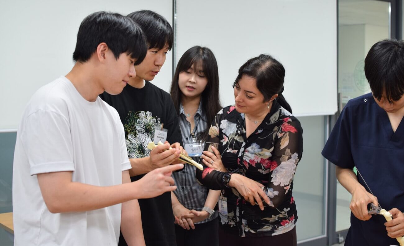 A bone is being examined by a group of adults in an academic setting.
