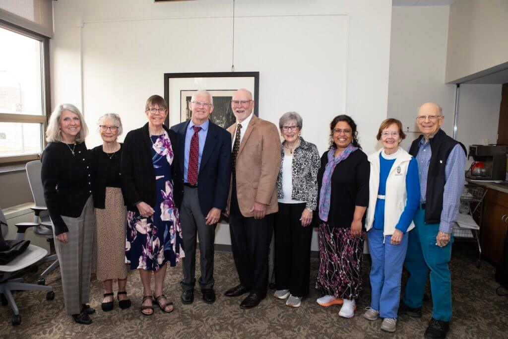 A large group of people stand together in front of a wall for  photograph.