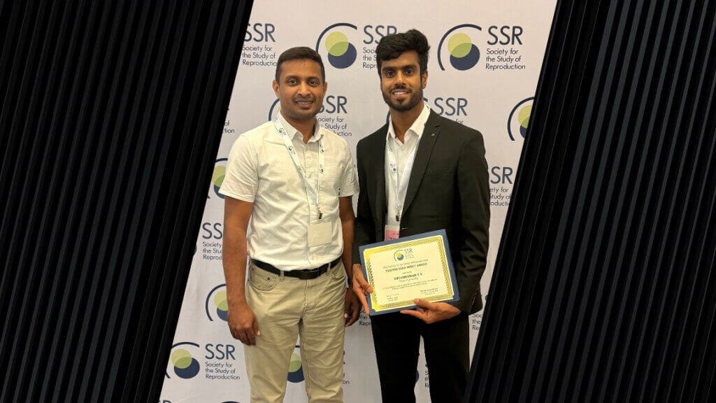 Two men are standing next to each other and are wearing business formal attire. The man on the right is holding a certificate award.