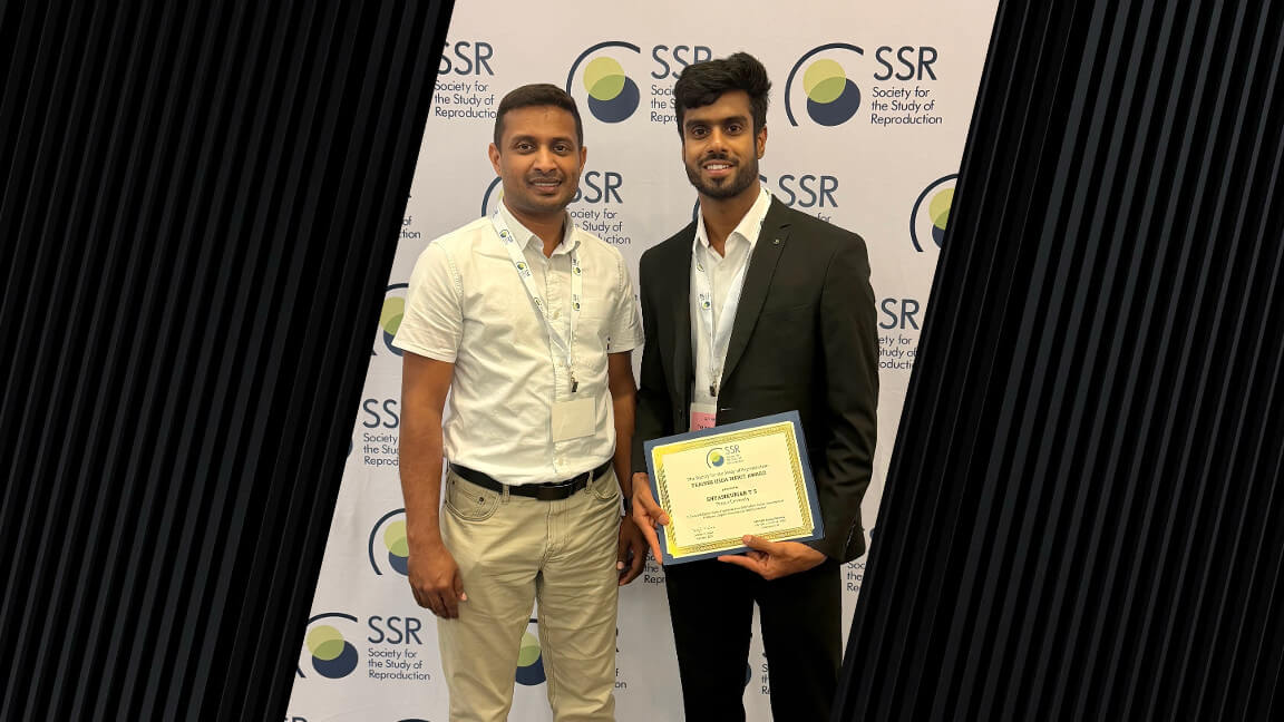 Two men are standing next to each other and are wearing business formal attire. The man on the right is holding a certificate award.