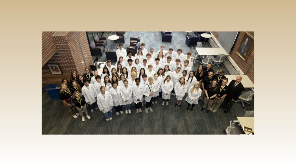 a birds-eye perspective photo of a group of students wearing white coats, posed for a photo