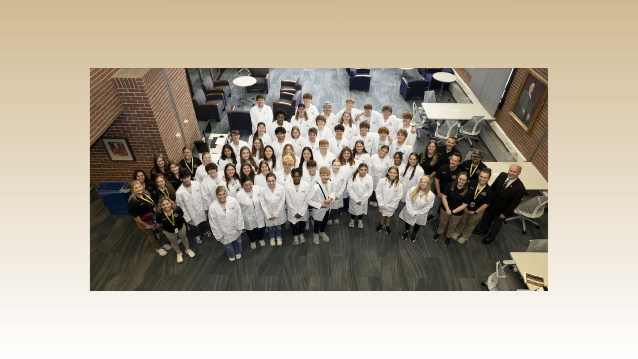a birds-eye perspective photo of a group of students wearing white coats, posed for a photo