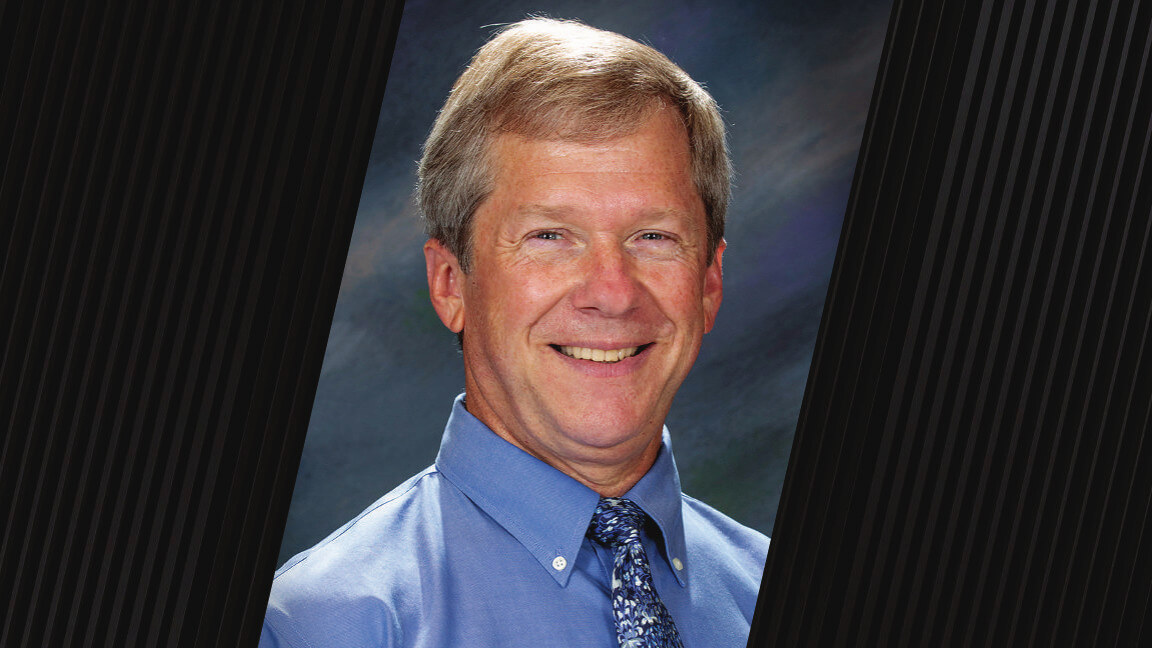 portrait of a man wearing a blue button up shirt and a blue floral-pattern tie