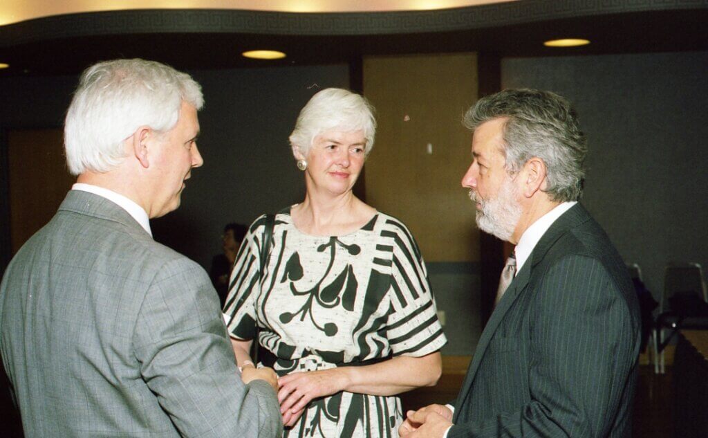three figures wearing business attire are gathered together in conversation